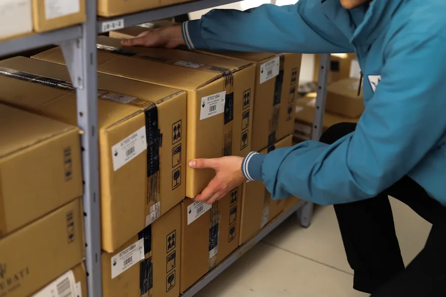 Originele Maserati-onderdelen in dozen op de stellingen van het magazijn