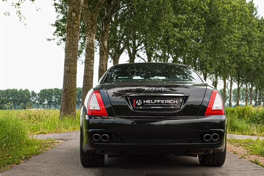 Zwarte Maserati Quattroporte van achteren op een landweg